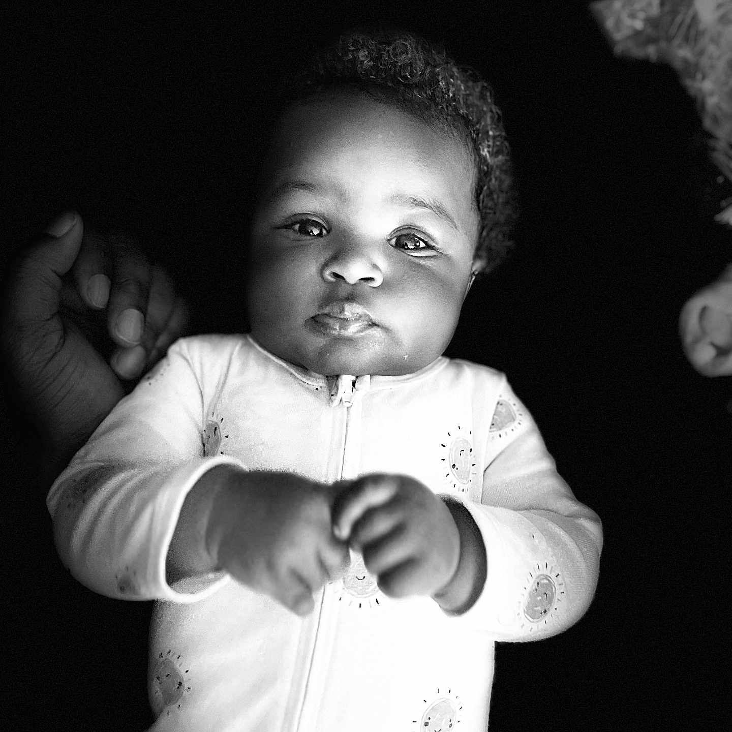 Caloni is registered to the contest to win money with this photo: baby, black_and_white, child, chubby_cheeks, curly_hair, cute, expression, eyes, face, hand, infant, monochrome, newborn, onesie, person, portrait, sleepwear, soft_lighting, support, young