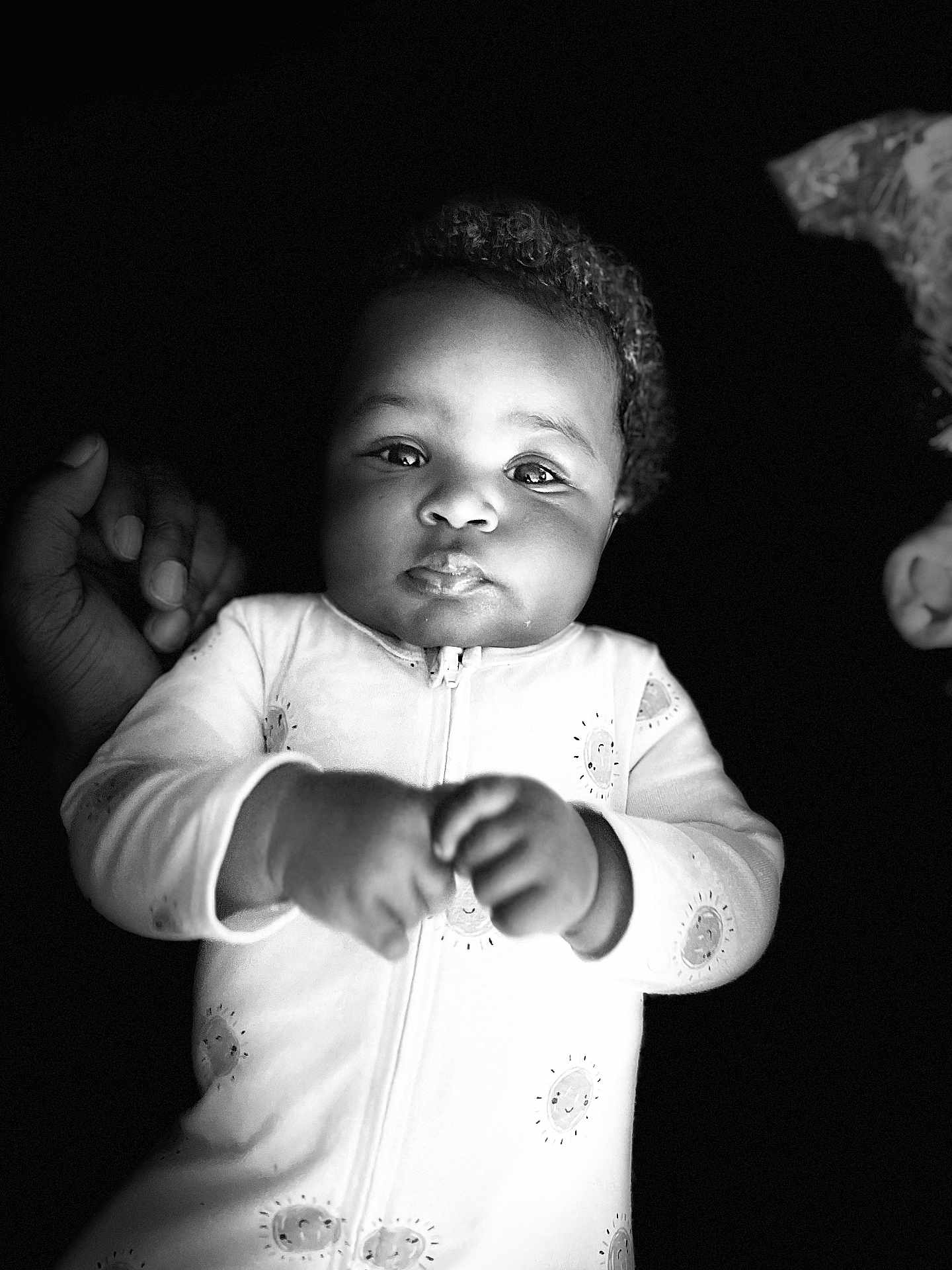 Caloni is registered to the contest to win money with this photo: baby, infant, child, portrait, black_and_white, onesie, hand, curly_hair, face, eyes, expression, cute, newborn, sleepwear, soft_lighting, support, chubby_cheeks, monochrome, young, person