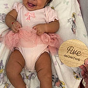 Elizabeth is registered to the contest to win money with this photo: baby, infant, smiling, pink_dress, socks, blanket, minnie_mouse, tutu, milestone, hand, wooden_sign, cute, happy, lying_down, child, portrait, celebration, soft_toys, cuteness, indoors