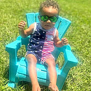 Omari is registered to the contest to win money with this photo: child, sunglasses, chair, outdoor, grass, sunny, blue, red, white, stars, stripes, summer, fashion, cute, person, feet, shorts, toddler, reflection, relaxing