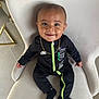 baby, child, smiling, black_clothing, nike, gold_chain, chair, indoor, portrait, cute, sitting, black_socks, floor, tile_floor, happy, young_child, fashion, person, head, face