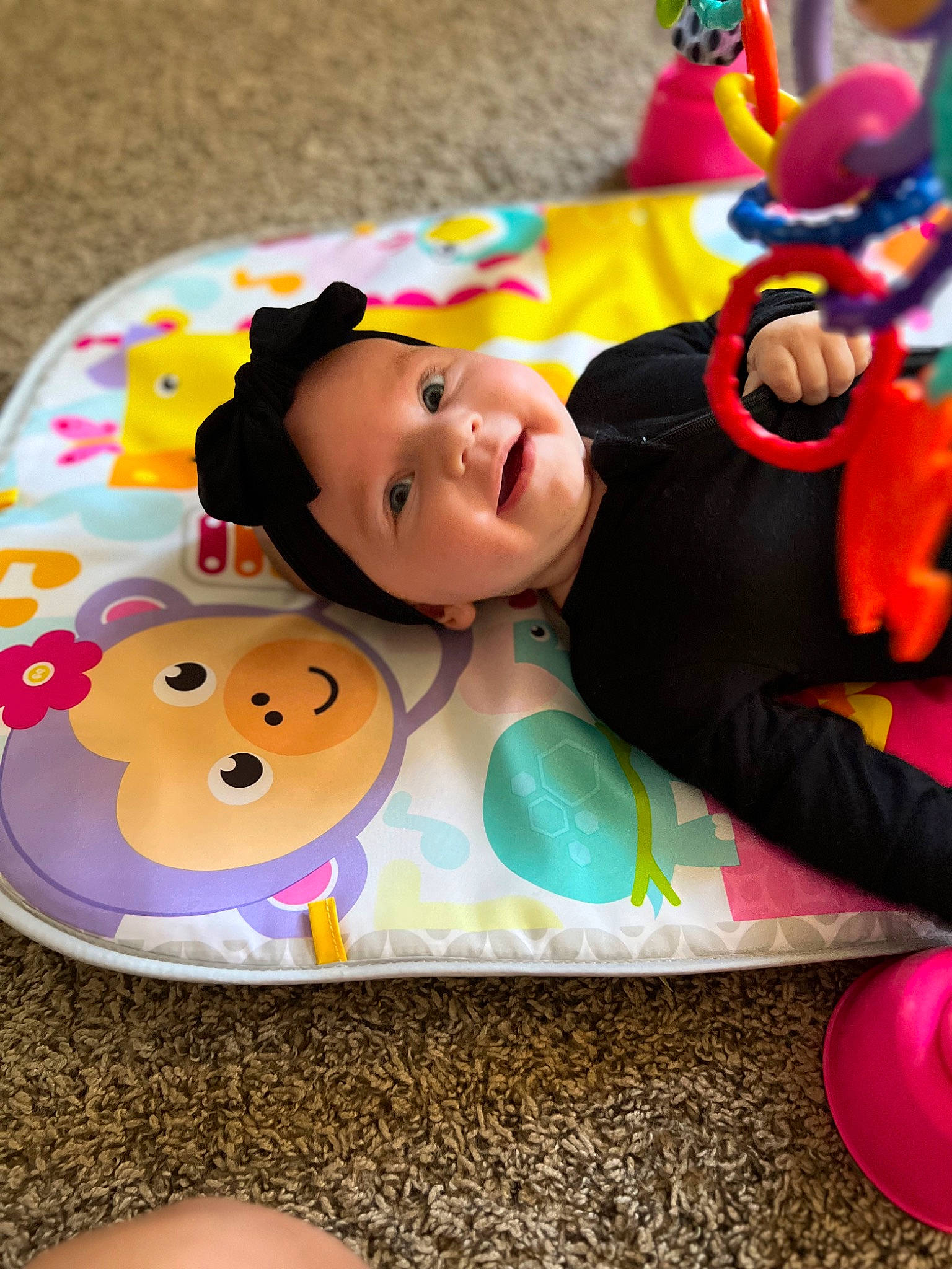 Lane is registered to the contest to win money with this photo: baby, baby_products, baby_toys, child, event, flooring, happy, headwear, leisure, pattern, person, pink, play, recreation, sitting, smile, stuffed_toy, sweetness, textile, toddler