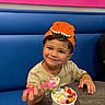 Caden joined the competition — help win amazing prizes! child, toddler, boy, smiling, portrait, dinosaur_hat, ice_cream, dessert, spoon, food, restaurant, booth, table, colorful, happy, sitting, indoor, close_up, striped_shirt, birthday_treat