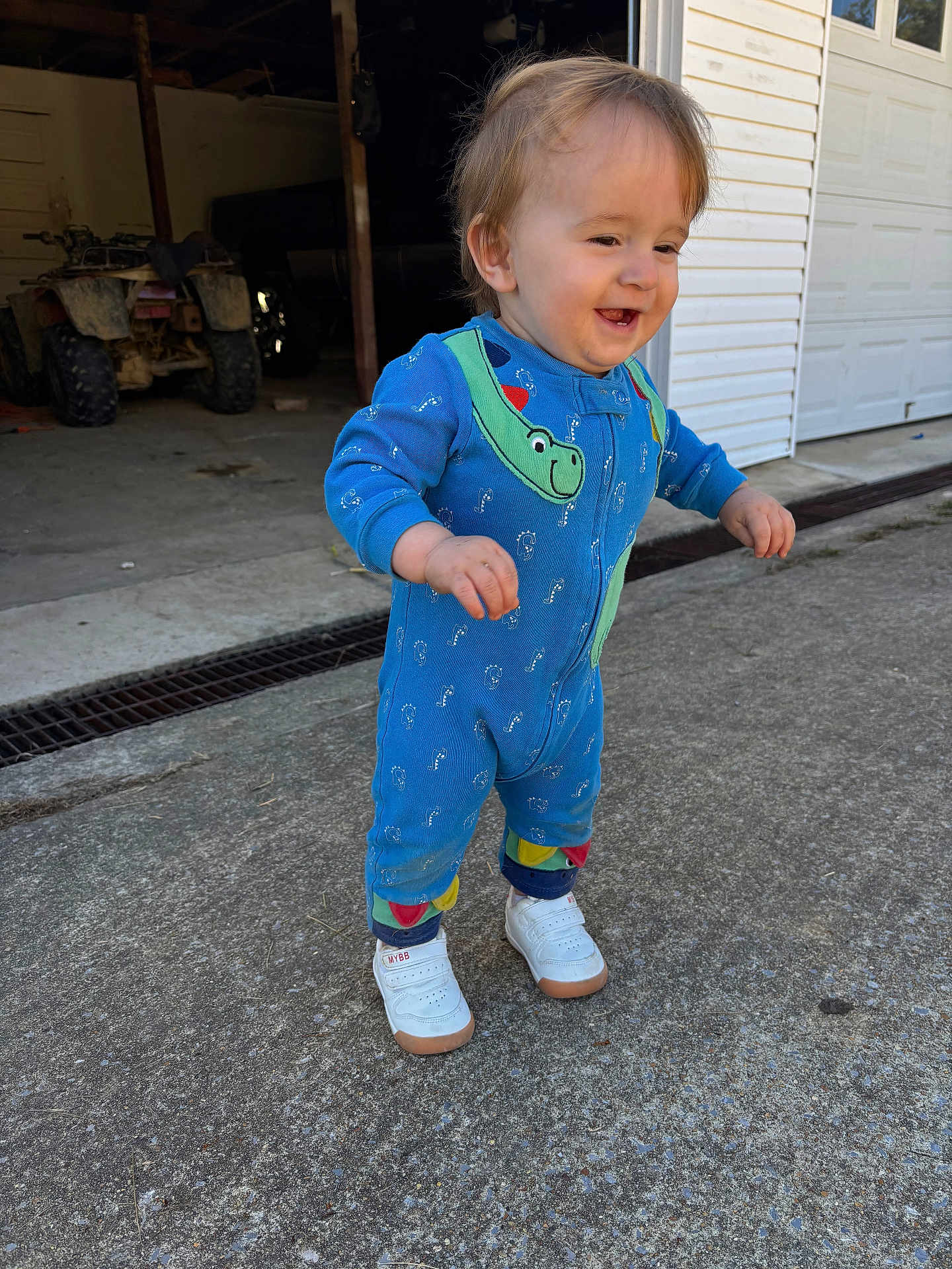 Kolter joined the competition — help win amazing prizes! toddler, child, blue_onesie, white_sneakers, smiling, outdoor, concrete, garage, atv, walking, happy, dinosaur_pattern, person, daylight, footwear, young_child, casual_clothing, concrete_driveway, sidewalk, expression
