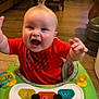 baby, child, walker, toy, piano_keys, smiling, happy, indoor, living_room, floor, furniture, television, red_shirt, hair, hands, seat, playtime, cute, infant, home