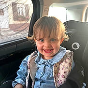 énora participe au concours pour gagner de l'argent avec cette photo : baby, blue_eyes, car_interior, car_seat, child, cute, denim_shirt, floral_pattern, hair, happy, indoor, person, portrait, safety, seatbelt, smile, sunlight, toddler, vest, window