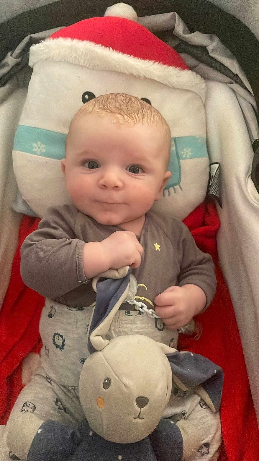 Tiago a rejoint le concours — aidez-le/la à gagner de superbes lots ! baby, infant, plush_toy, stroller, pillow, santa_hat, onesie, pacifier_clip, blanket, red_blanket, smile, eyes, hands, sitting, cozy, soft_toys, portrait, nursery, closeup, cute