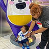 Zamir joined the competition — help win amazing prizes! toddler, child, adult, birthday, ribbon, money, statue, cartoon, winking_face, purple, yellow, white, blue, indoor, floor, tile, person, clothing, socks, playful