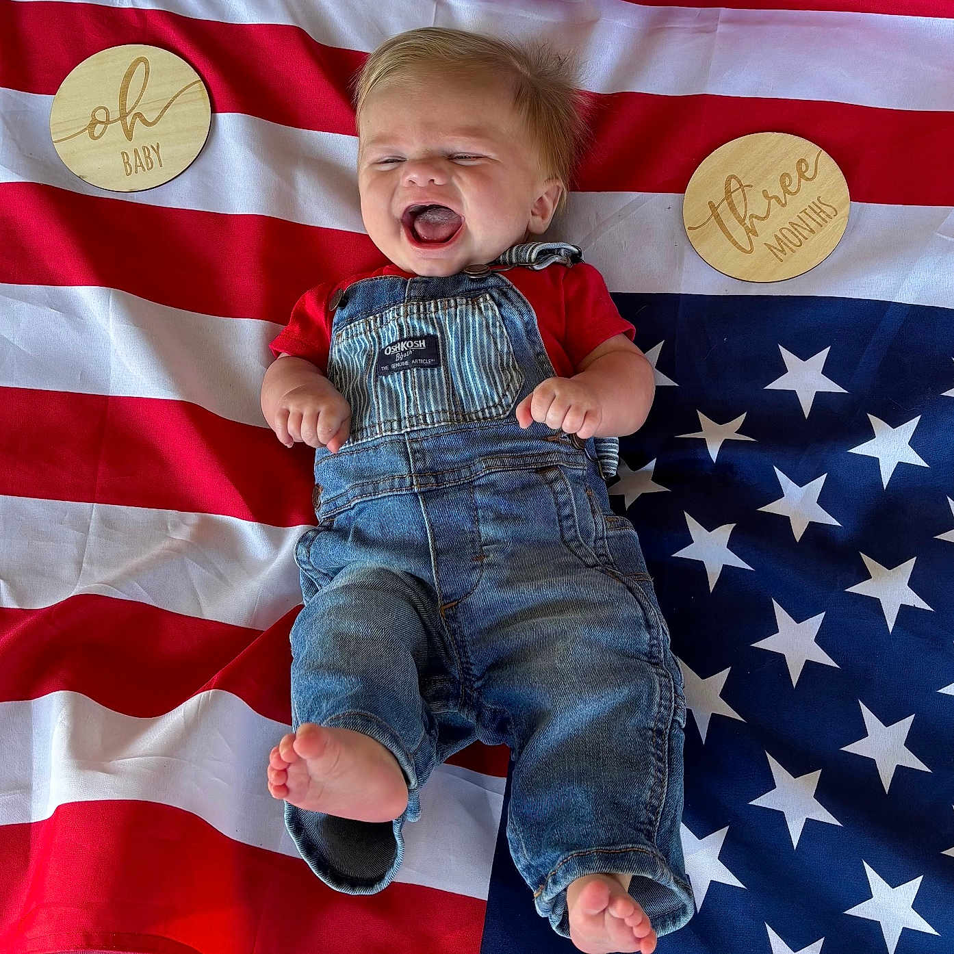 Grant joined the competition — help win amazing prizes! american_flag, baby, barefoot, celebration, child, clothing, cute, denim_overalls, happy, infant, laughing, lying_down, milestone, oh_baby, portrait, red_shirt, stars, stripes, three_months, wooden_plaques