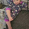 toddler, child, pajamas, smile, face, hair, ponytail, couch, blanket, carpet, floor, indoor, relaxed, playful, cute, person, clothing, patterned, happy, resting