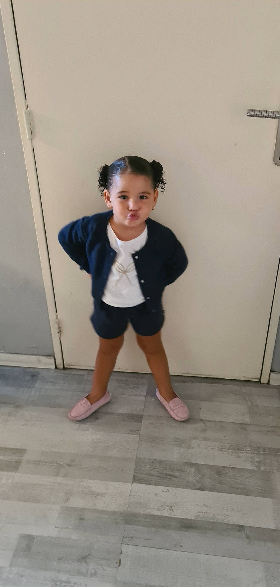 Ynaïa participe au concours pour gagner de l'argent avec cette photo : baby_toddler_clothing, collar, door, floor, flooring, foot, fun, happy, human_leg, joint, knee, person, sitting, sleeve, sock, standing, t_shirt, thigh, toddler, waist