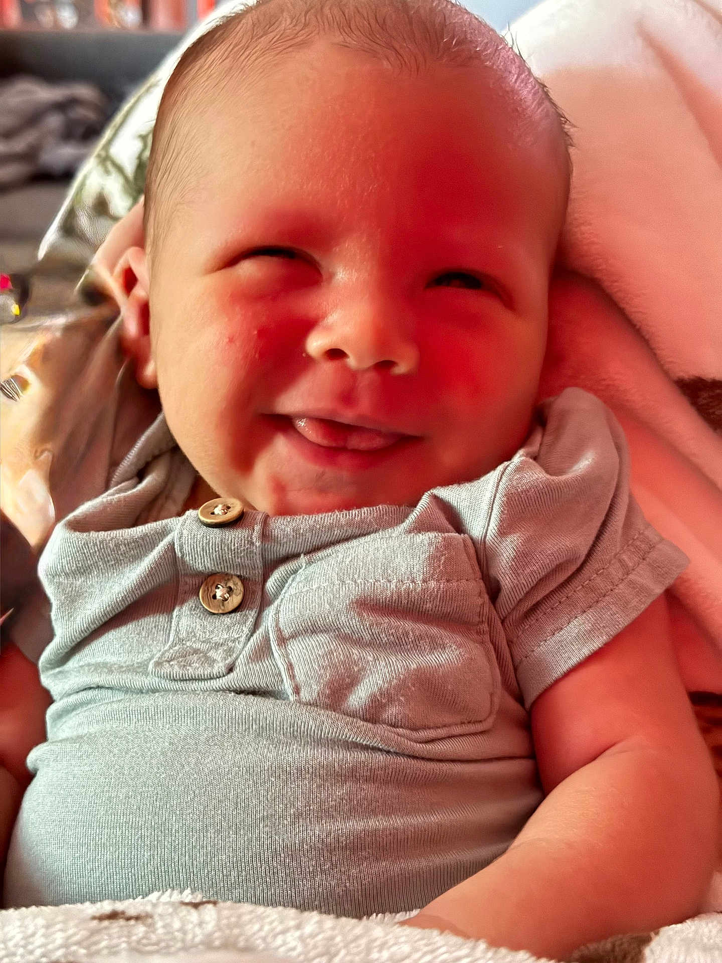 Stetson is registered to the contest to win money with this photo: baby, infant, smile, tongue, face, clothing, grey_shirt, buttons, blanket, soft_texture, cute, happy, skin, newborn, portrait, closeup, child, indoors, warm_light, cozy