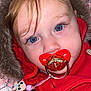 baby, beads, blanket, blue_eyes, cartoon_character, child, close_up, clothing, cute, face, fur_hood, hand, indoors, infant, pacifier, pink, portrait, red_clothing, toy, warm