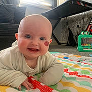 Daisy joined the competition — help win amazing prizes! baby, infant, smiling, face, birthmark, play_mat, indoor, toy, couch, keyboard_stand, carpet, child, happy, clothing, person, cute, expression, floor, home, colorful