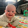 baby, infant, smiling, face, birthmark, play_mat, indoor, toy, couch, keyboard_stand, carpet, child, happy, clothing, person, cute, expression, floor, home, colorful