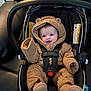 baby, car_seat, infant, onesie, fuzzy_clothing, smiling, blue_eyes, seatbelt, cute, child, indoor, clothing, mitten, footwear, safety, happy, person, small, teddy_bear_style, seat
