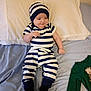 baby, bed, bedroom, blanket, child, clothing, comfort, cute, green_onesie, hat, infant, lying_down, pajamas, pillow, relaxed, sleepwear, smiling, socks, soft_fabric, striped_clothing