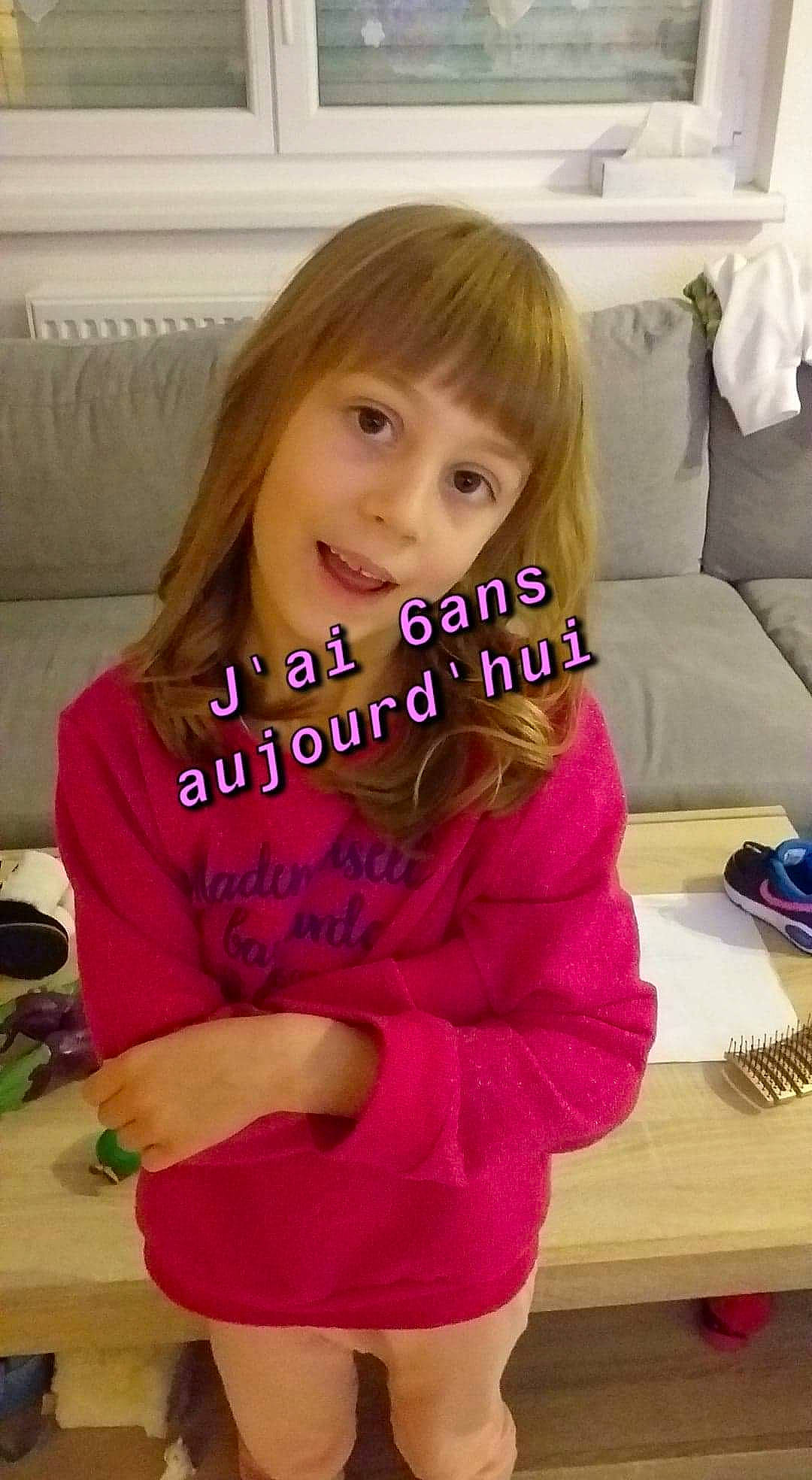 Mélina participe au concours pour gagner de l'argent avec cette photo : arm, couch, eyelash, facial_expression, finger, hair, hairstyle, happy, human, joint, muscle, neck, person, shoulder, skin, sleeve, smile, standing, table, thigh