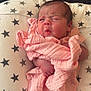 baby, newborn, infant, pink_blanket, wrapped, face, expression, cushion, star_pattern, lying_down, soft_texture, skin, head, hand, sleeping_area, indoors, cute, small, child, portrait