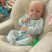 Haizley is registered to the contest to win money with this photo: baby, pacifier, chair, plush_chair, toy, indoor, window, blanket, car_seat, floor, child, person, couch, light, soft_furniture, clothing, infant, living_room, cute, relaxing