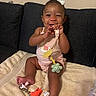 Jae'Onti is registered to the contest to win money with this photo: baby, child, girl, smiling, bow, pacifier, toy, blanket, couch, indoors, happy, cute, sitting, infant, clothing, accessory, face, feet, hand, playful