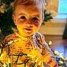 toddler, child, baby, face, smile, lights, fairy_lights, christmas_tree, holiday, indoors, portrait, warm_light, pajamas, floor, hand, decorations, cozy, cute, young_child, festive