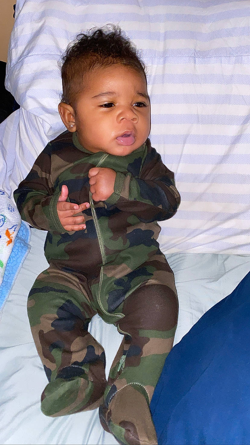 Cyier Brown joined the competition — help win amazing prizes! baby, baby_toddler_clothing, camouflage, child, comfort, face, finger, gesture, hand, happy, human_leg, leg, military_camouflage, mouth, person, skin, sleeve, textile, thigh, thumb