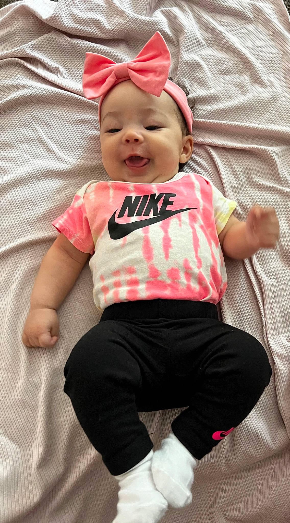 Kaylani is registered to the contest to win money with this photo: baby, baby_laughing, baby_toddler_clothing, baseball_cap, cap, child, comfort, eye, face, fun, happy, head, headwear, linens, magenta, pattern, person, pink, sleeve, smile