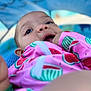 Isla is registered to the contest to win money with this photo: baby, child, face, closeup, pink_clothing, watermelon_pattern, hand, finger_in_mouth, blue_background, tent, curious_expression, outdoor, infant, portrait, young_child, cute, colorful, soft_focus, head, skin