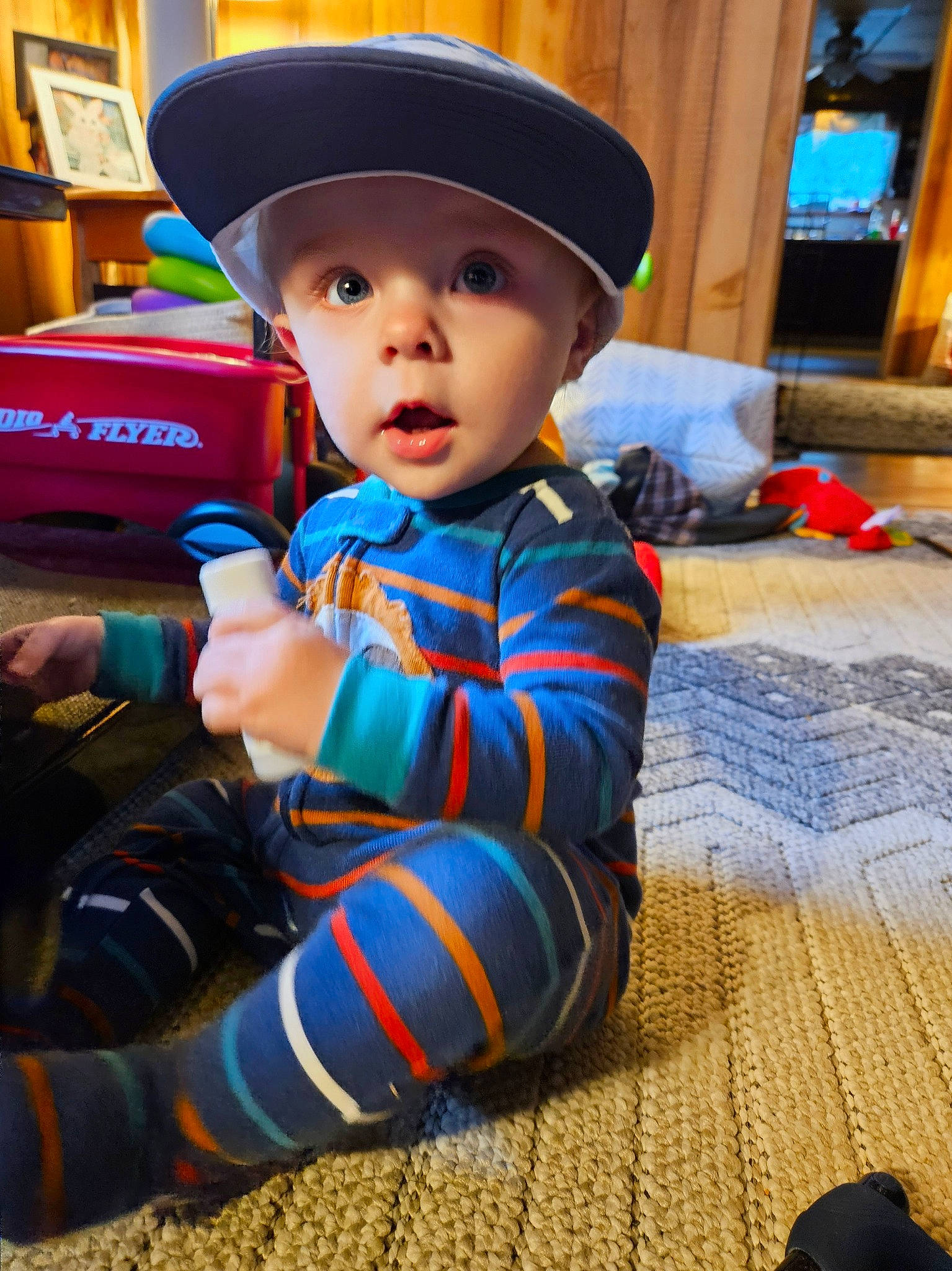 Daxtyn is registered to the contest to win money with this photo: baby, baby_toddler_clothing, bookcase, cap, child, costume_hat, electric_blue, fictional_character, flooring, fun, hat, headwear, houseplant, pattern, person, personal_protective_equipment, room, shelf, sitting, surprise