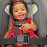 baby, baby_girl, black_hair, car_safety, car_seat, child, close_up, cute, expression, hair_bows, happy, indoors, infant, person, portrait, red_dress, safety, seat_belt, smile, straps