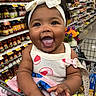Amaia joined the competition — help win amazing prizes! baby, smiling, shopping_cart, grocery_store, headband, bow, clothing, blanket, happy, child, person, aisle, food, jars, shelf, colorful, cute, portrait, infant, hand
