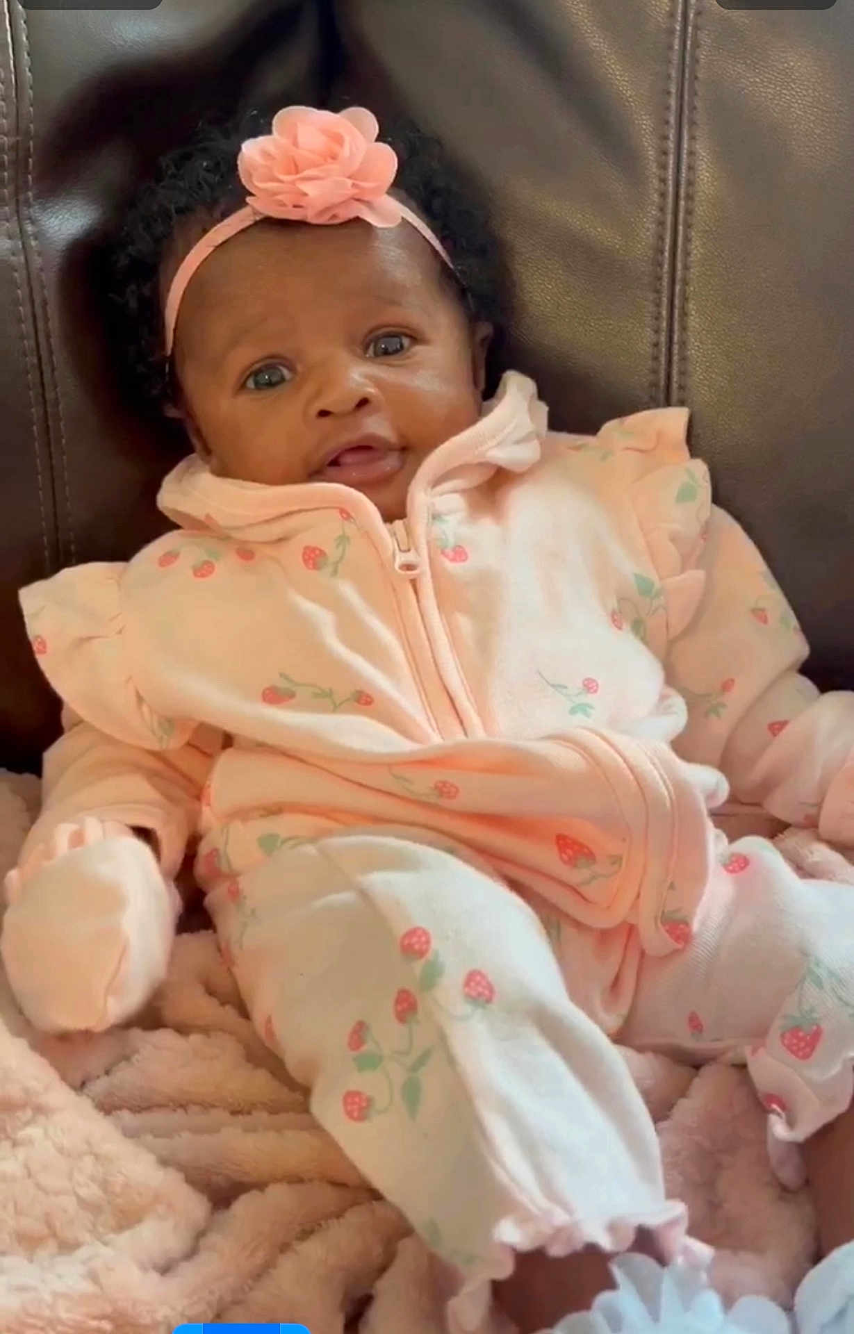 Naiari is registered to the contest to win money with this photo: baby, infant, pink_clothing, headband, flower, couch, blanket, soft_texture, curly_hair, cute, portrait, child, indoor, cozy, sitting, comfort, young_child, looking_at_camera, small_hands, adorable