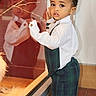 toddler, child, reflection, glass, window, curious, indoor, plaid, pants, white_shirt, standing, portrait, young_child, fashion, cute, expression, warm_lighting, curly_hair, floor, background