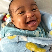 Luis is registered to the contest to win money with this photo: baby, smiling, blanket, blue, infant, cute, happy, face, child, wrapped, soft, clothing, indoors, closeup, head, skin, cheeks, joy, portrait, babywear