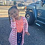 child, girl, braids, pink, cardigan, denim_skirt, white_shoes, outdoor, gravel, truck, mountains, smiling, posing, daylight, casual_clothing, happy, portrait, person, cute, ribbons