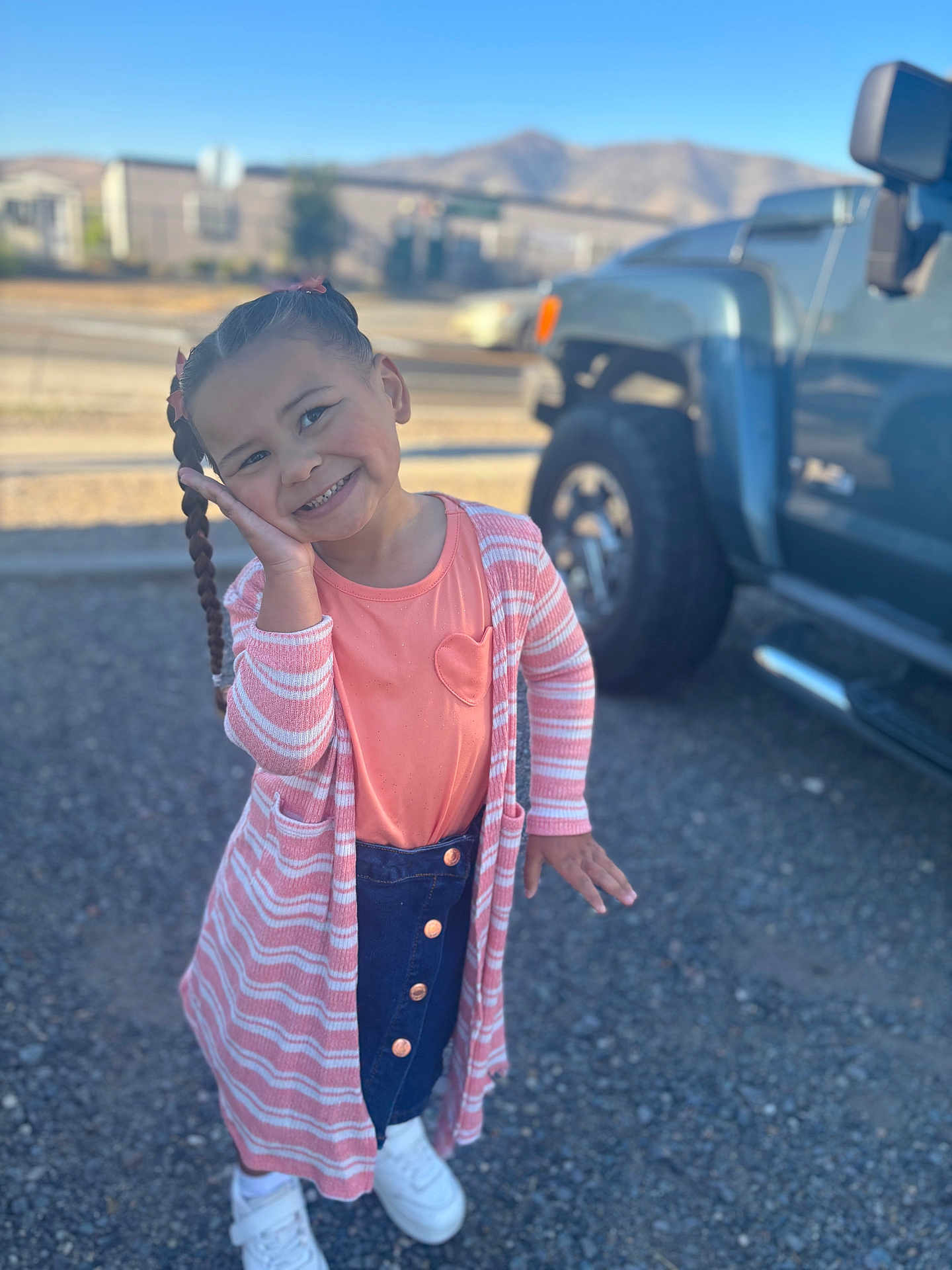 Dorothy joined the competition — help win amazing prizes! child, girl, braids, pink, cardigan, denim_skirt, white_shoes, outdoor, gravel, truck, mountains, smiling, posing, daylight, casual_clothing, happy, portrait, person, cute, ribbons