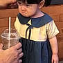 Dorothy is registered to the contest to win money with this photo: blue_dress, brick_wall, child, cute, dress, expression, grumpy_face, hair, hand, indoors, person, plastic_cup, portrait, pout, refusal, short_sleeves, straw, toddler, yellow_top, young_child
