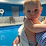 Levi is registered to the contest to win money with this photo: baby, towel, indoor_pool, child, tattoo, person, water, blue_wall, chair, window, hand, skin, diaper, plaster, swimming, portrait, expression, holding, infant, room
