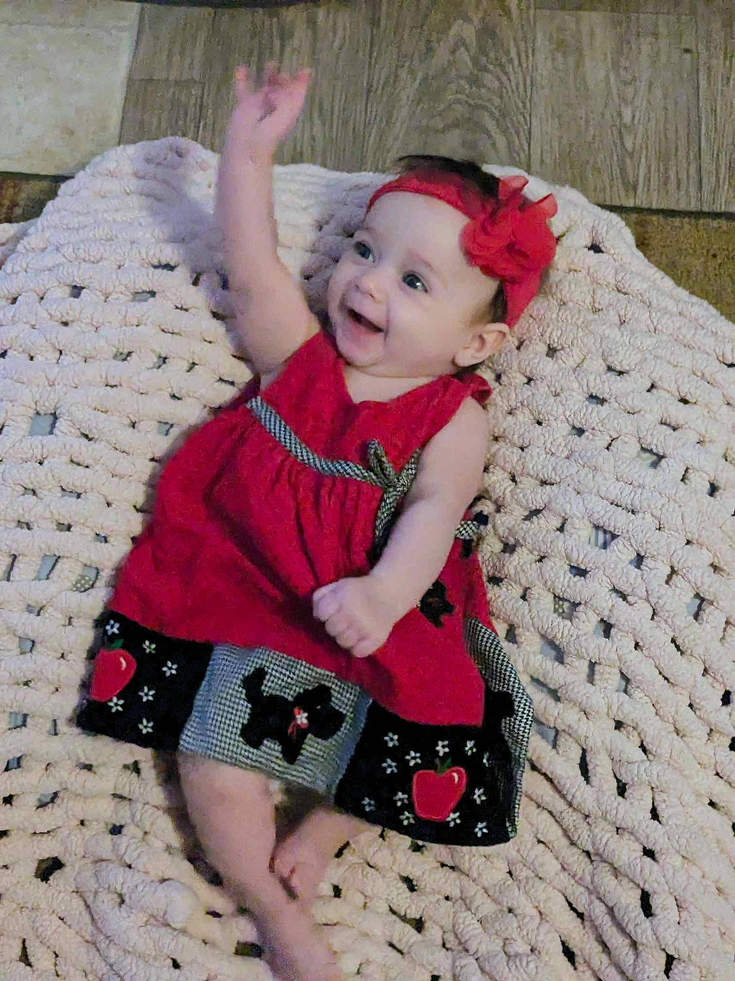 Beatrice is registered to the contest to win money with this photo: baby_toddler_clothing, comfort, day_dress, dress, embellishment, headwear, human_body, human_leg, joy, leg, magenta, pattern, person, pink, plant, sitting, skin, sleeve, smile, sock
