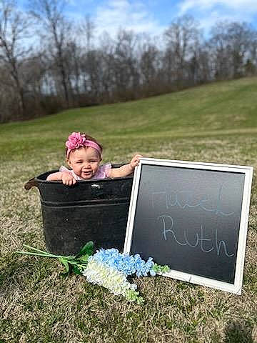 Hazel is registered to the contest to win money with this photo: baby, cloud, electric_blue, field, flash_photography, grass, grass_family, grassland, happy, landscape, leisure, meadow, people_in_nature, person, plant, shrub, sitting, sky, soil, toddler