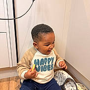 Bryson joined the competition — help win amazing prizes! toddler, child, happy, smiling, indoor, floor, clothing, sweatshirt, blue_pants, blanket, snack, wooden_floor, corner, person, cute, short_hair, playful, casual, home, cozy