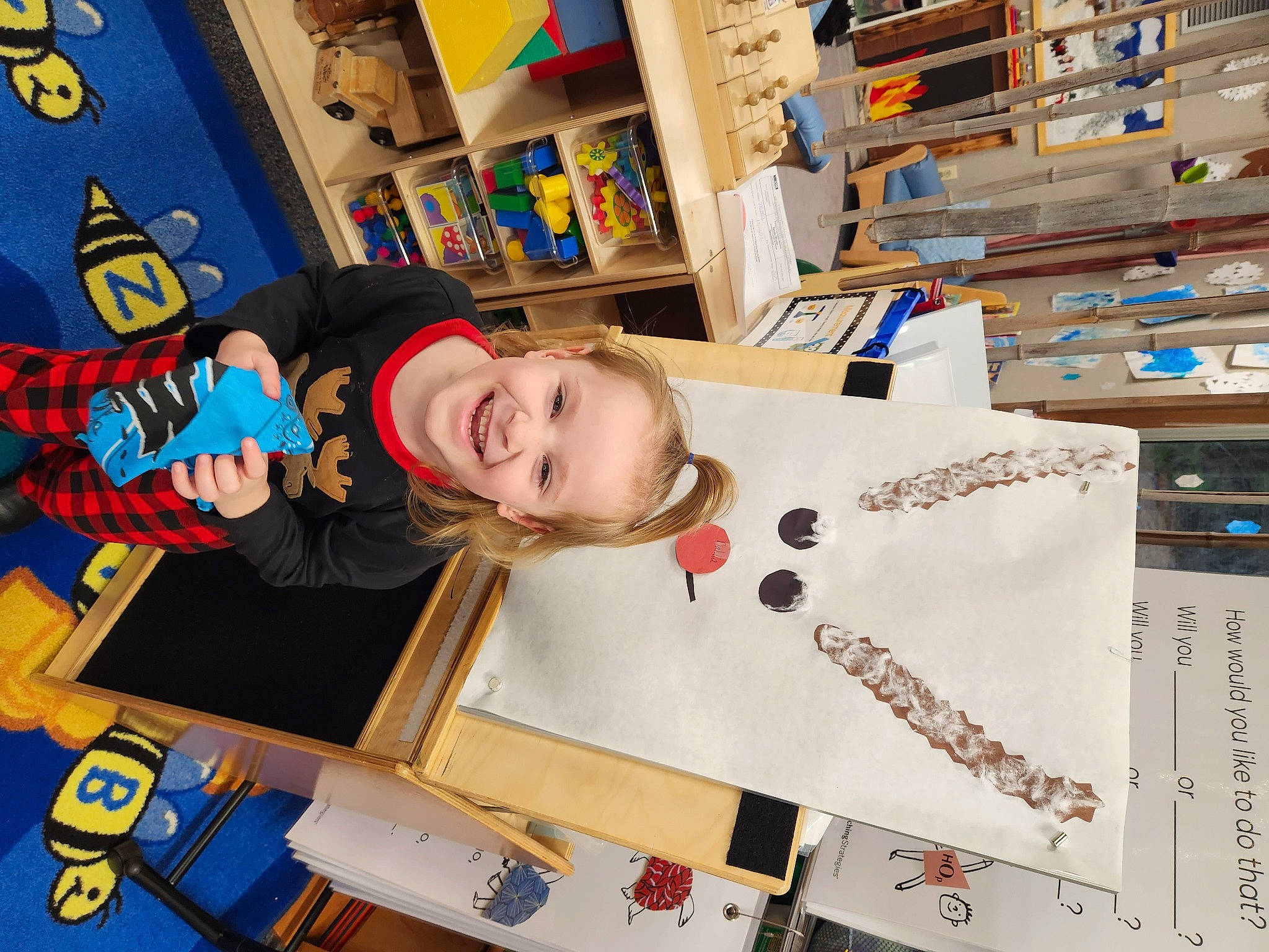 Dahlia is registered to the contest to win money with this photo: child, fun, happy, joy, kindergarten, learning, office_supplies, person, play, ring_binder, room, school, shelf, shelving, smile, t_shirt, toddler, wood