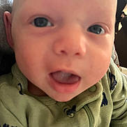 Oliver is registered to the contest to win money with this photo: baby, close_up, face, infant, child, green_clothing, open_mouth, eyes, skin, cute, young, portrait, person, indoors, soft_focus, apparel, childhood, expression, head, baby_garment