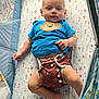 baby, infant, child, playpen, blue_shirt, monkey_graphic, diaper, patterned_diaper, hot_air_balloon_pattern, mattress, lying_down, barefoot, cute, curious, indoor, soft_lighting, plush, baby_clothing, person, face