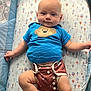 baby, infant, smiling, blue_shirt, monkey_design, diaper_cover, playpen, blanket, hot_air_balloon_pattern, cute, child, toddler, lying_down, indoors, happy, clothing, person, young_child, skin, arms
