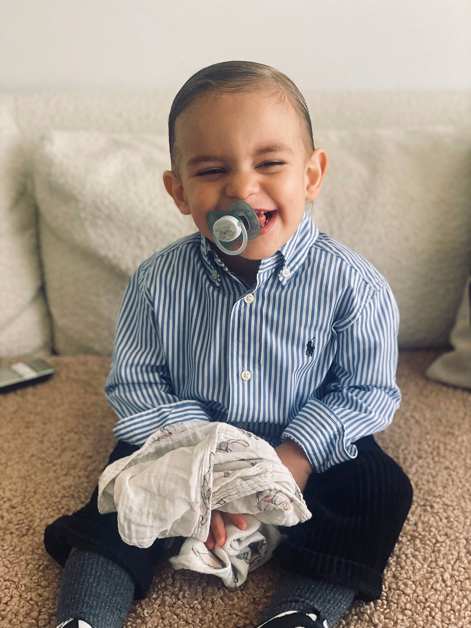 Izaac a rejoint le concours — aidez-le/la à gagner de superbes lots ! baby, baby_toddler_clothing, child, collar, comfort, dress_shirt, floor, flooring, foot, grey, human_leg, joy, linens, pattern, person, sitting, skin, sleeve, smile, standing