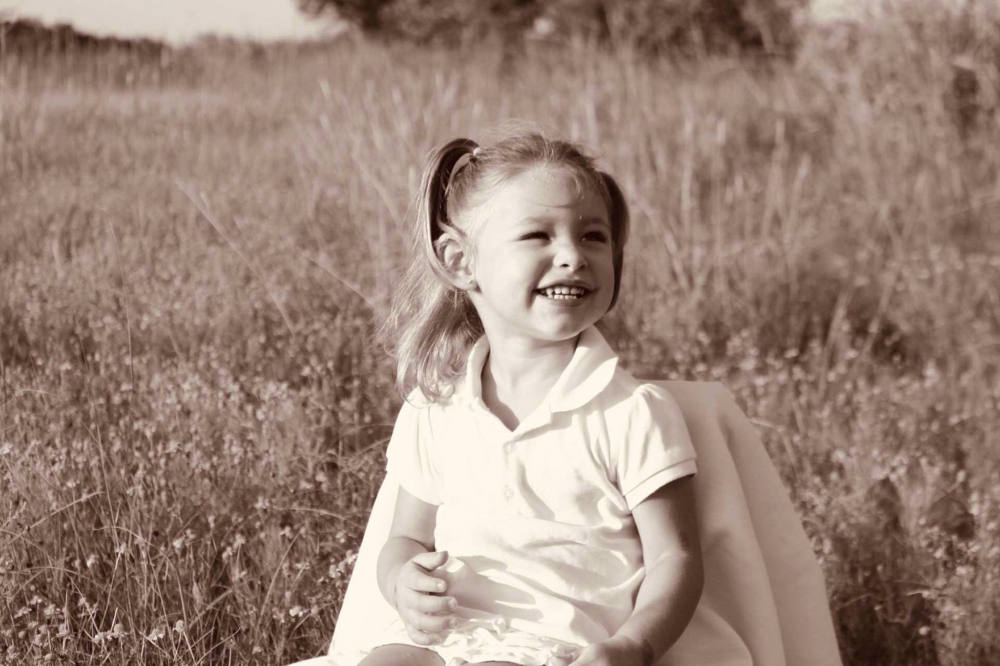 Gypsy is registered to the contest to win money with this photo: black_and_white, child, facial_expression, grass, grass_family, happy, joy, laugh, monochrome, monochrome_photography, people, people_in_nature, person, photograph, photography, portrait, portrait_photography, sitting, smile, snapshot