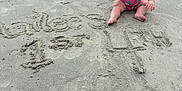 Hailee joined the competition — help win amazing prizes! baby, child, beach, sand, swimsuit, pink, sitting, portrait, outdoor, footprints, writing, celebration, first_birthday, serious_expression, water, summer, vacation, nature, person, fun