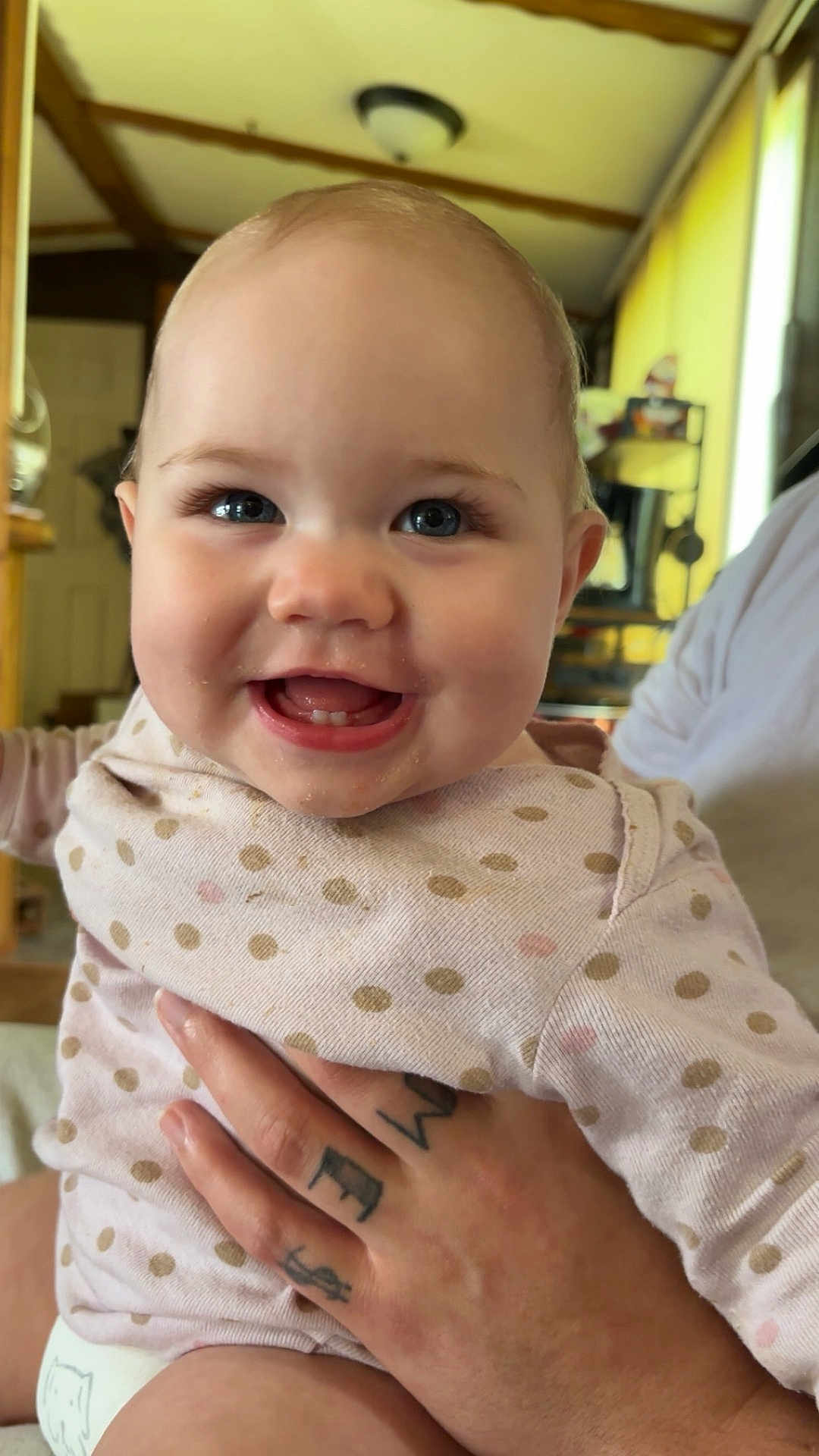 Hailee joined the competition — help win amazing prizes! baby, child, smiling, face, person, hand, tattoo, clothing, polka_dot, indoor, home, light, wooden_beam, eyes, mouth, cheeks, happy, cute, infant, portrait